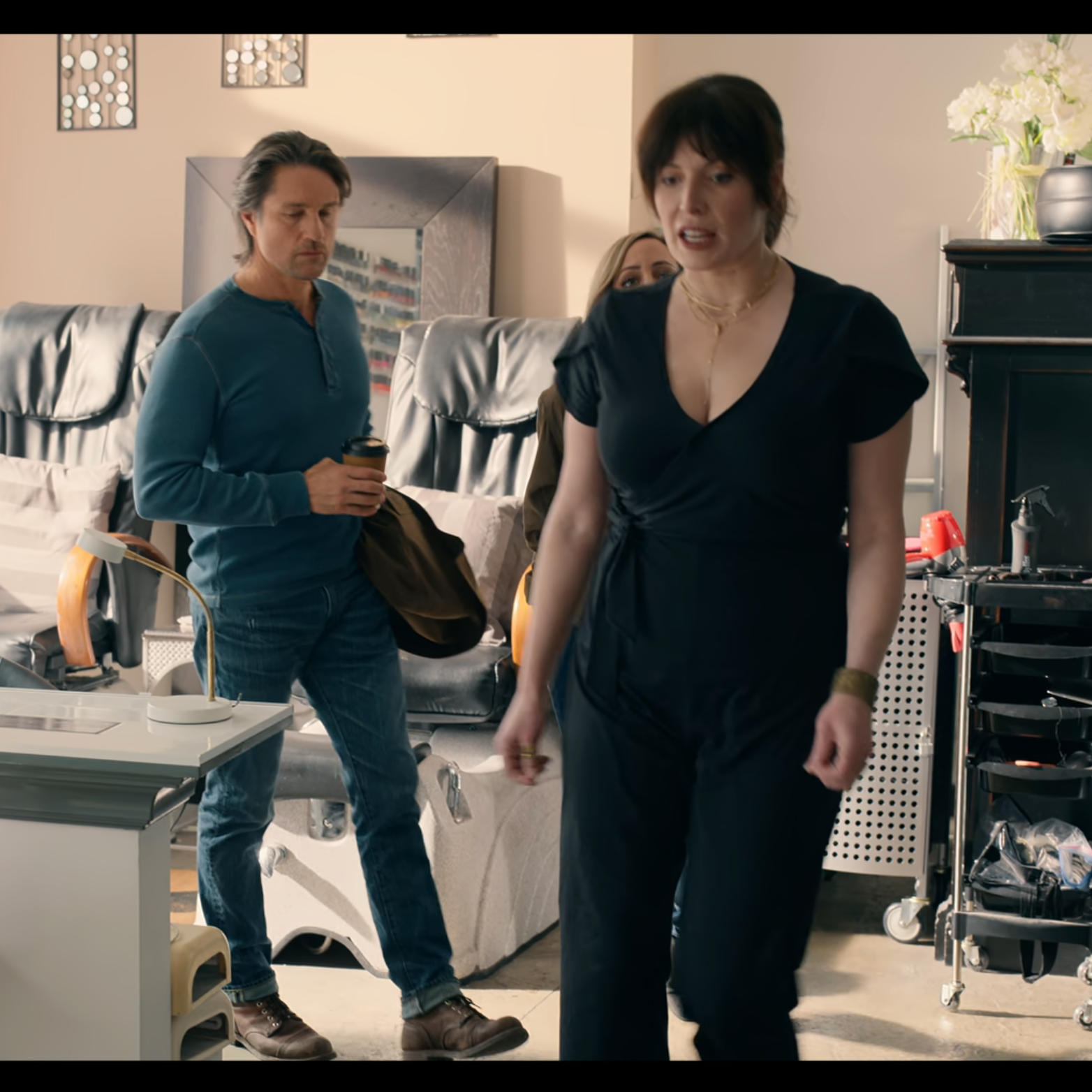 Two people walking through a modern office space with furniture and decor.